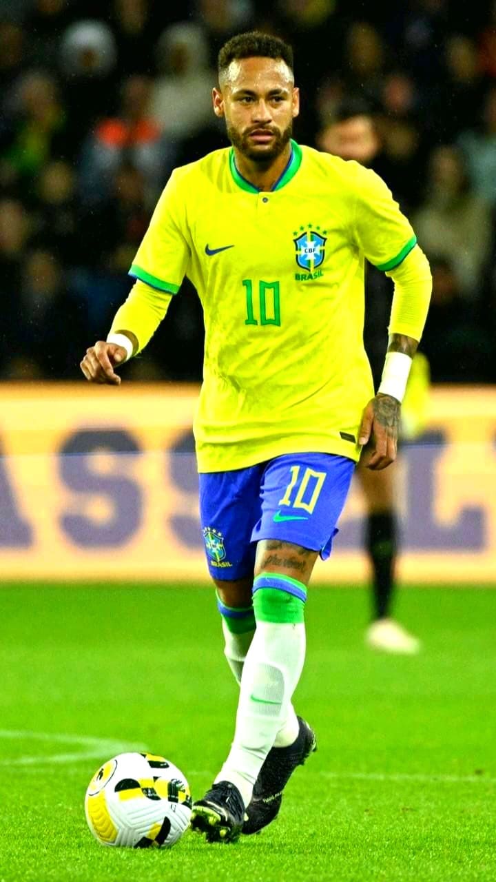 A male soccer player in a yellow Brazil jersey with the number 10 dribbles a soccer ball on the field. He is wearing blue shorts and white socks, as fans cheer from the stadium—perfect action to enjoy live on Latino IPTV.
